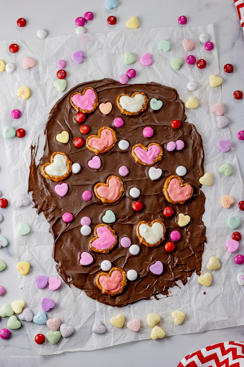 Spread out chocolate topped with Valentine's candies and pretzels