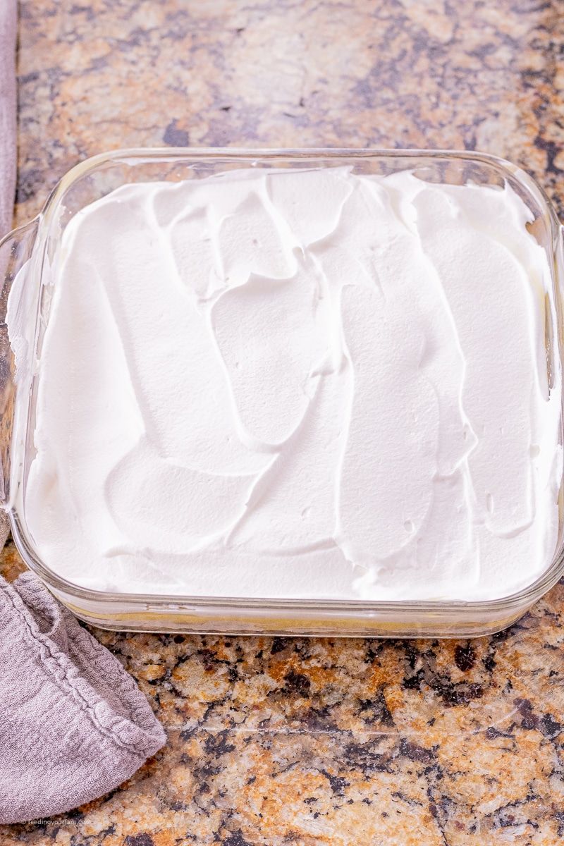 banana layer cake with cookie crust banana pudding and whipped topping in a square baking dish