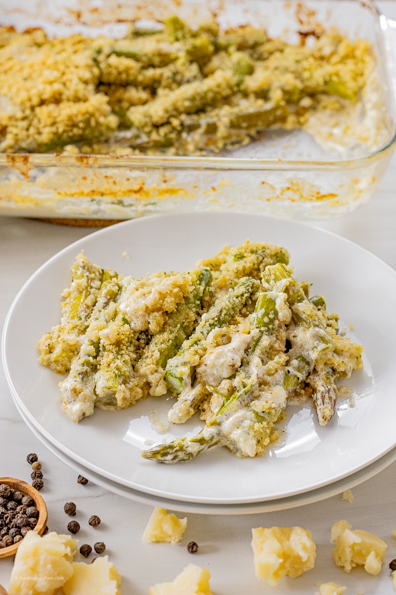 sliced asparagus baked in parmesan cream sauce on a white plate