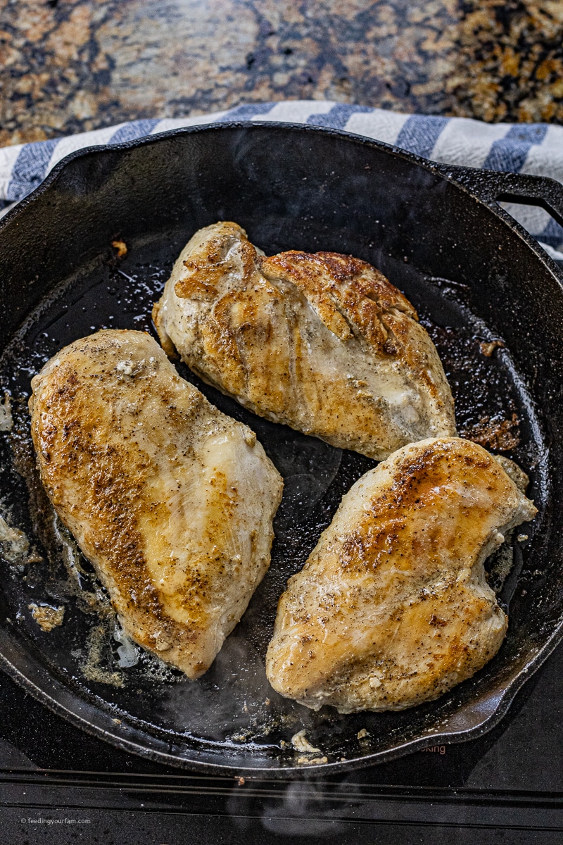 3 chicken breasts that have been cooked in a black cast iron skillet