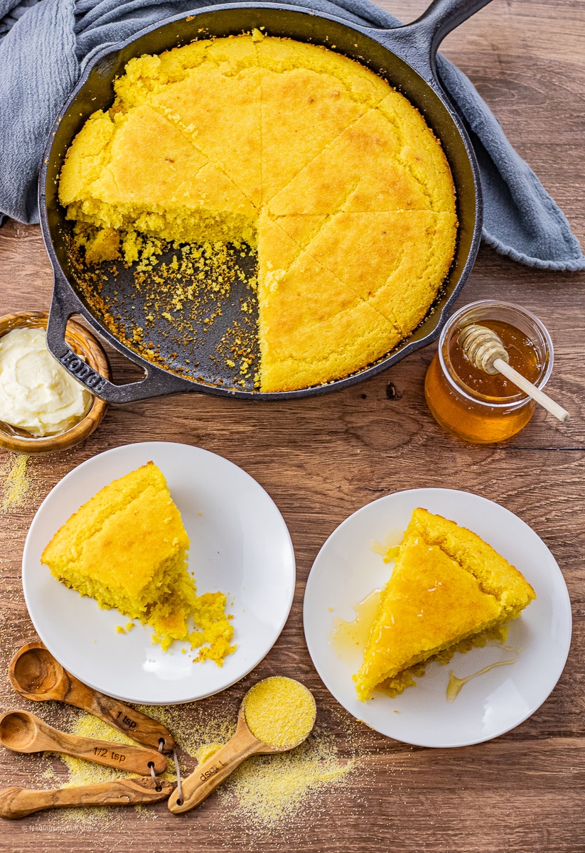 Cornbread in a cast iron bread with triangular slices on a white plate