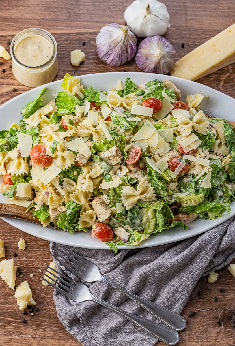 caesar salad with chicken and bowtie pasta on a serving platter
