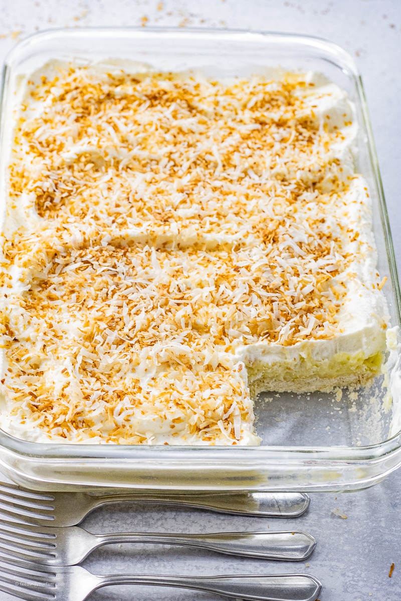 coconut cream pie bars in a glass baking dish with a square cut out of the pan