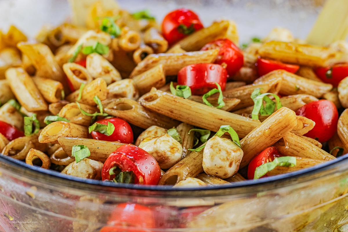 pasta salad made with penne pasta, sliced tomatoes and mozzarella cheese balls