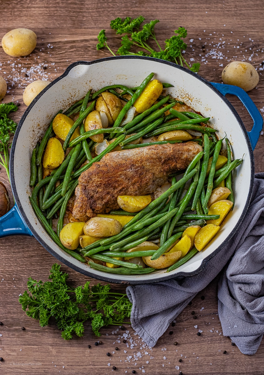 pork tenderloin cooked in the oven in a cast iron pan with potatoes and green beans