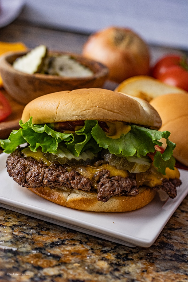 smashed burger on a brioche bun topped with melted cheese, lettuce, pickles and tomatoes