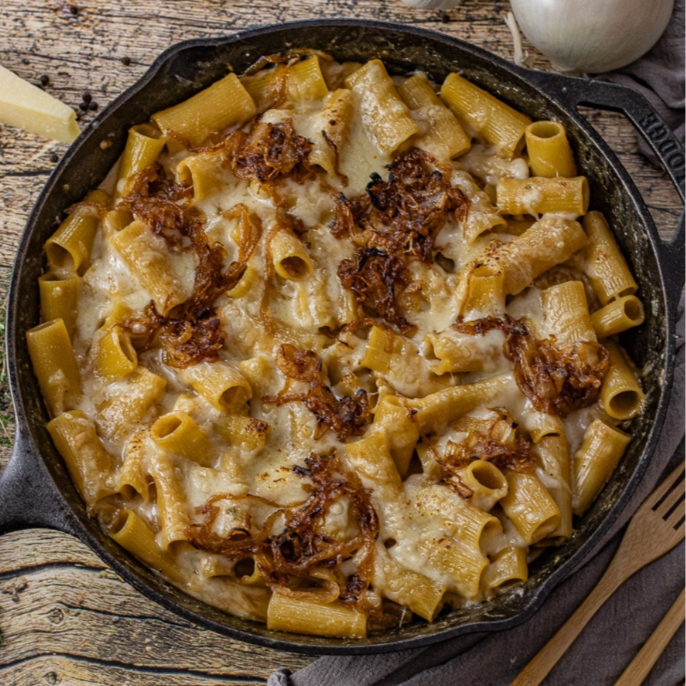mac and cheese topped with caramelized onions in a skillet