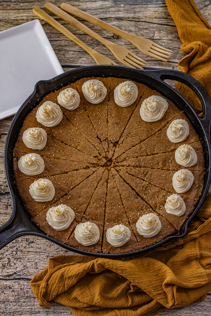 cast iron skillet with a gingerbread cookie baked in it topped with cream cheese frosting
