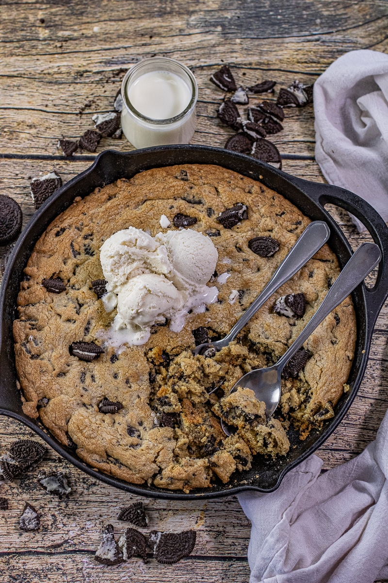 cookies and cream cookie baked in a cast iron skillet and topped with scoops of vanilla ice cream