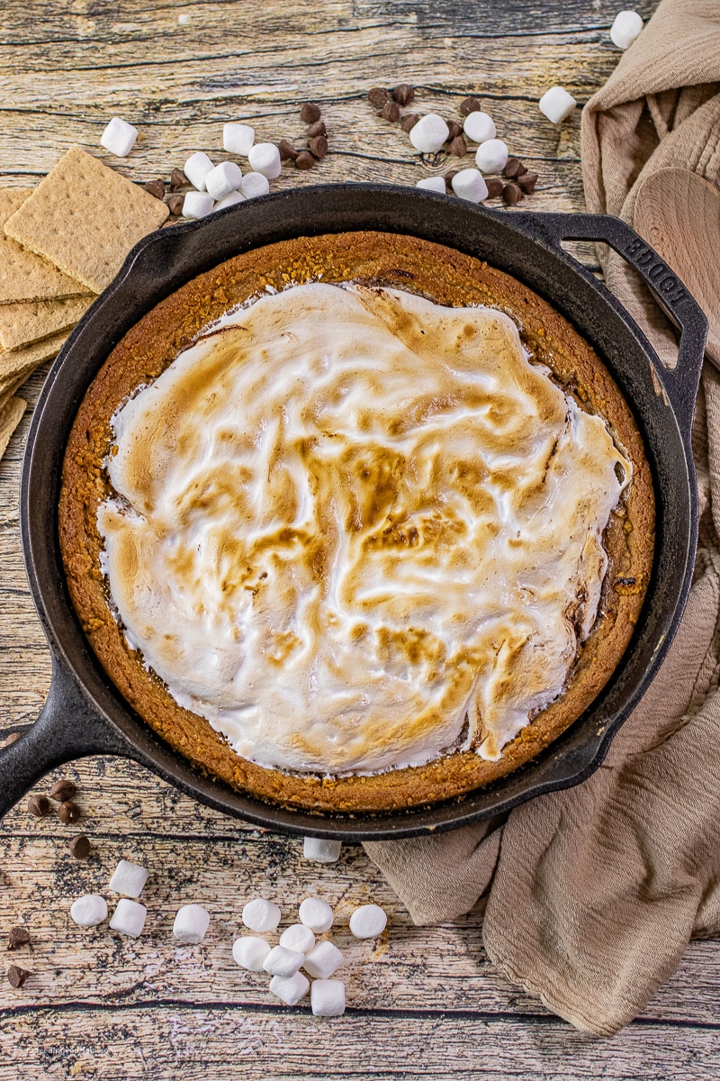 Gooey s’mores cookie baked in a cast iron skillet with toasted marshmallows and melted chocolate on top