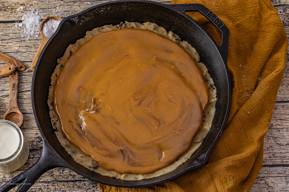 chocolate chip cookie topped with melted caramel in a cast iron skillet