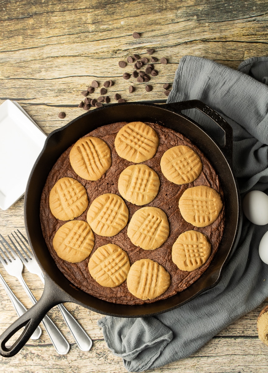 brownie topped with peanut butter cookies in a cast iron skillet