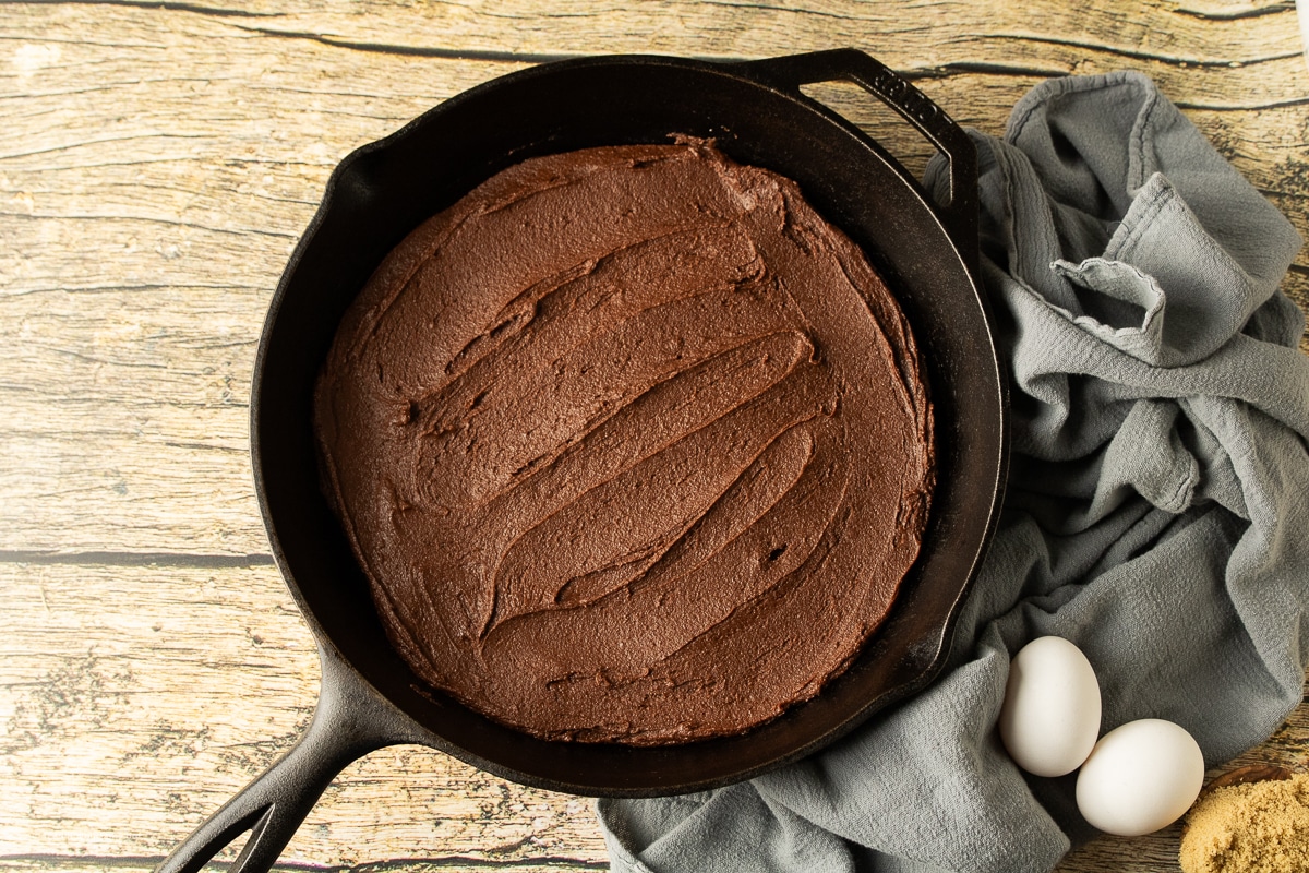 brownie batter spread in a cast iron skillet