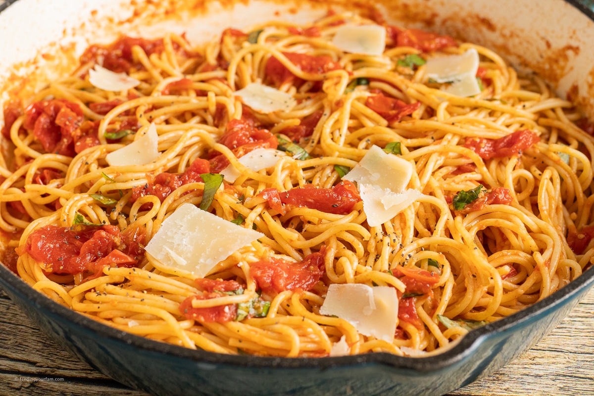 pasta with cherry tomato sauce topped with shaved parmesan and basil
