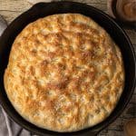top view of a golden brown focaccia bread baked in a cast iron skillet