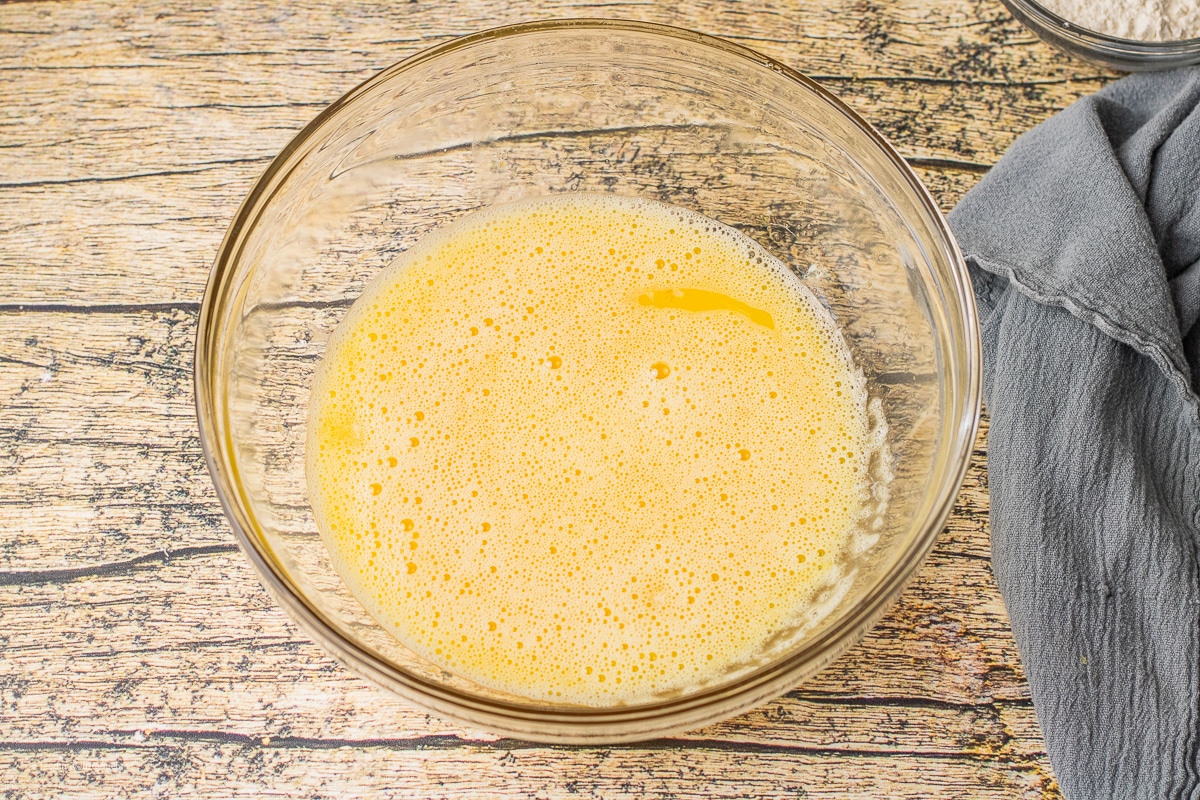 eggs whisked with sugar in a glass mixing bowl