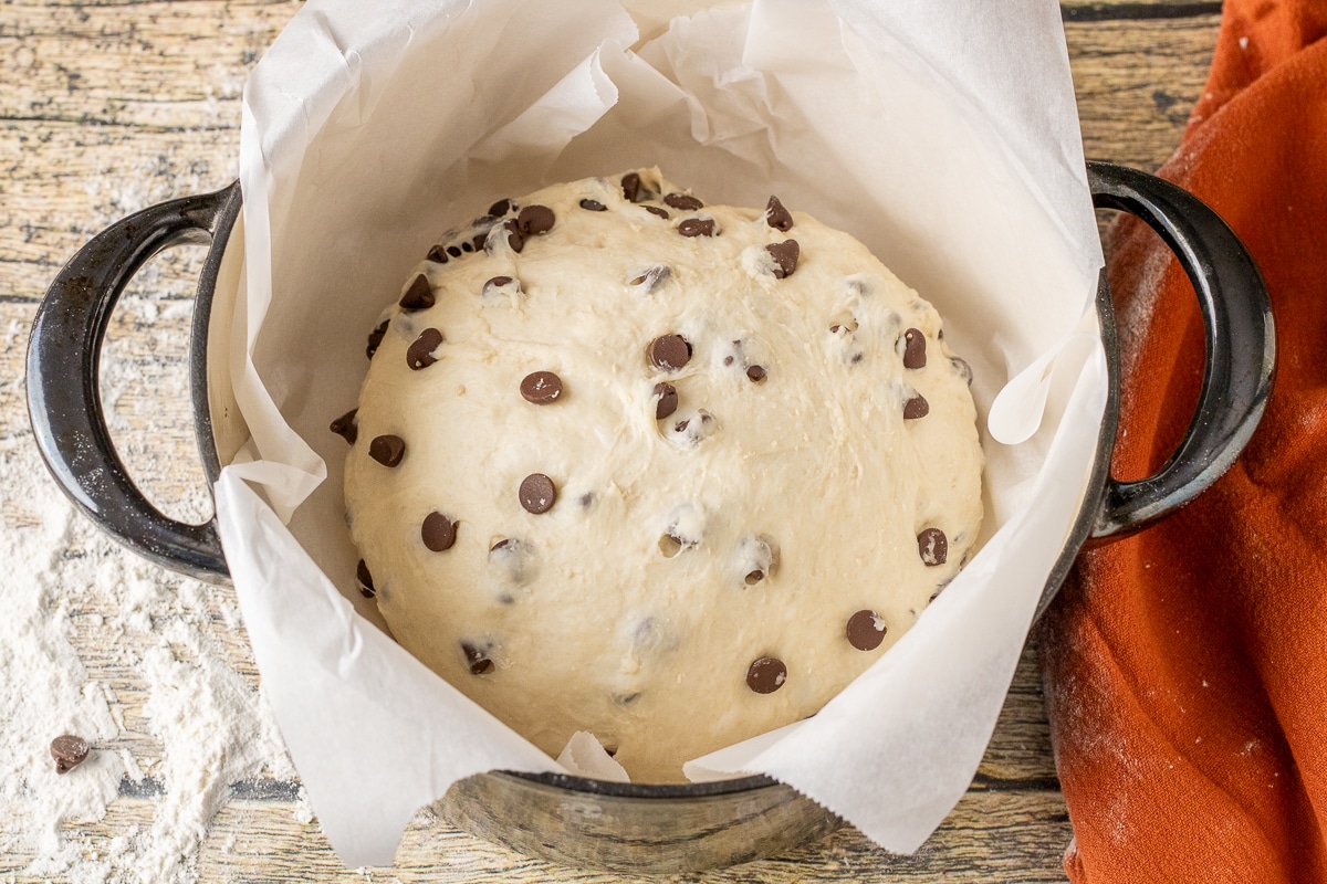 chocolate chip bread in a cast iron dutch oven pan lined with parchment paper.