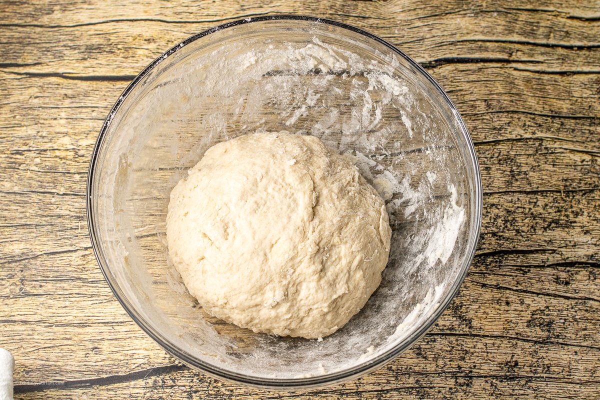 bread dough in a ball in a glass mixing bowl
