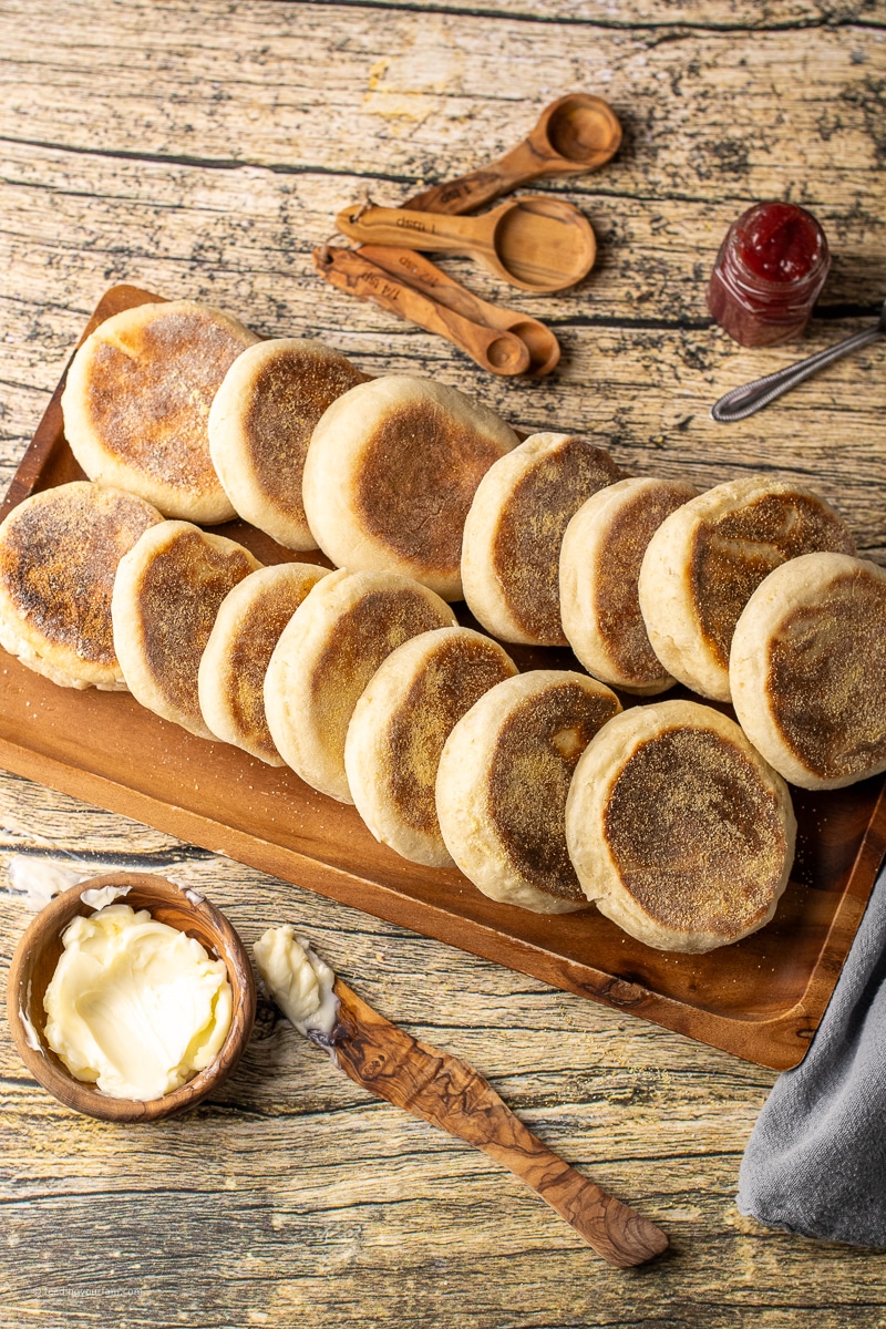 soft, chewy English muffins layered on a wooden platter. 