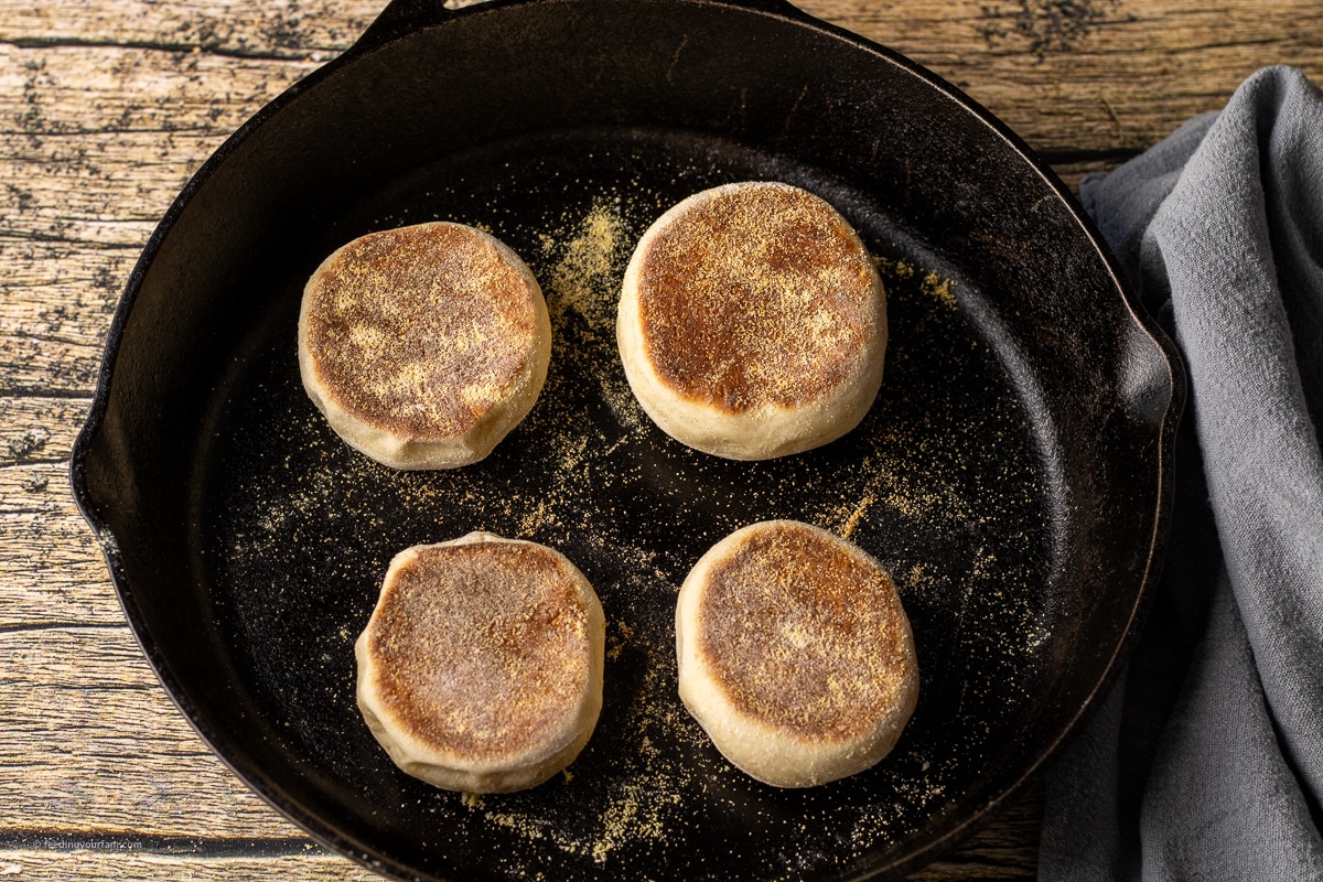 cooking English muffins in a black cast iron skillet