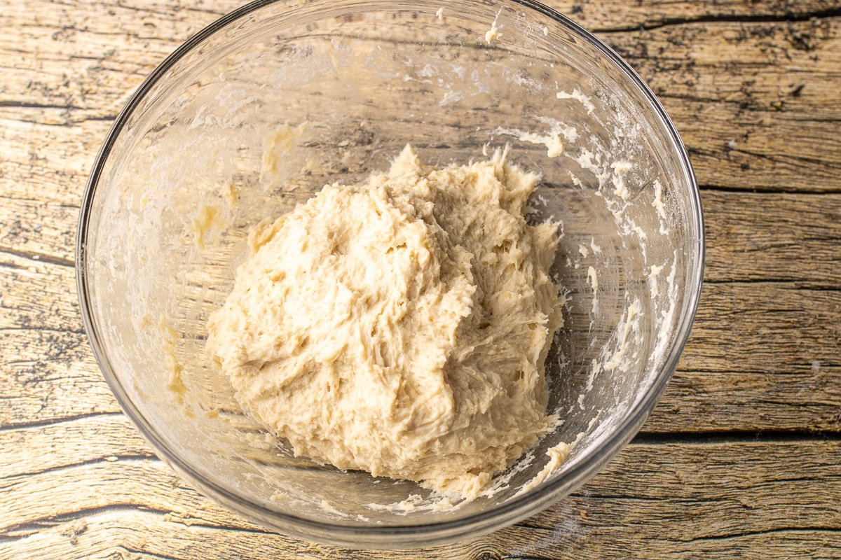 shaggy dough in a glass mixing bowl used to make homemade english muffins
